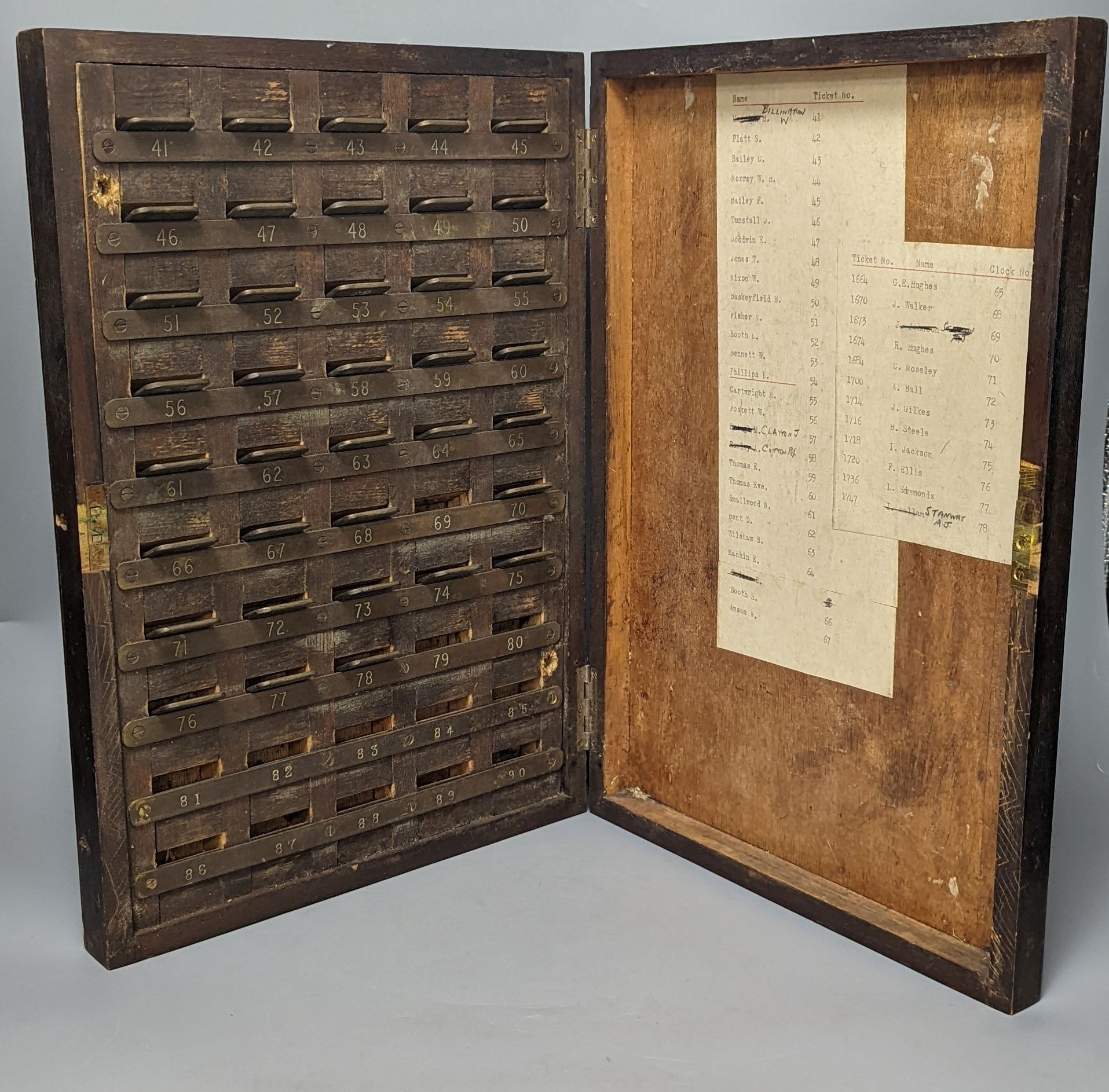 An early 20th century textile mill clocking in board with engraved numbered tokens